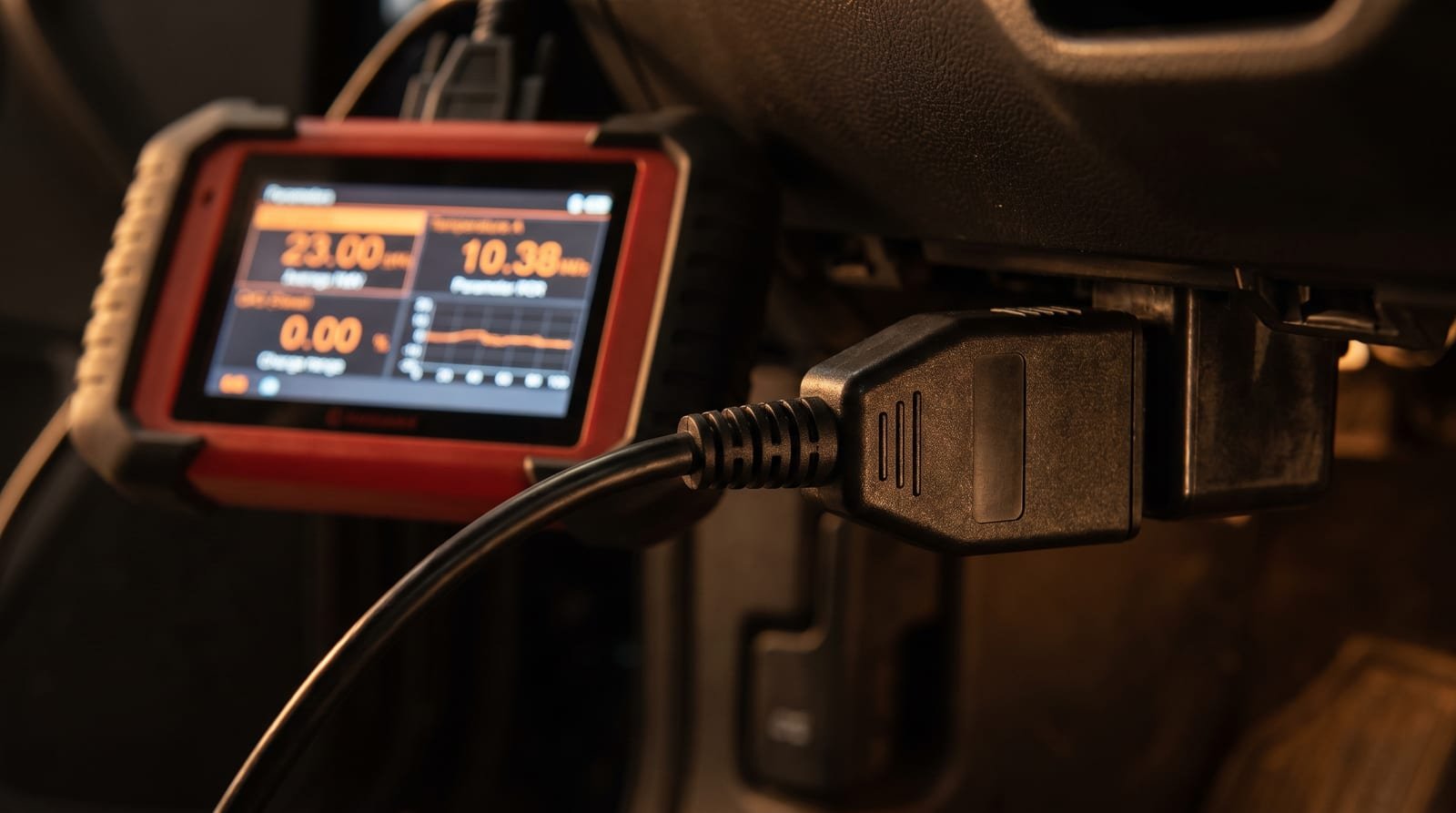 Conector de diagnóstico OBD enchufado al vehículo, con el equipo leyendo los parámetros del motor